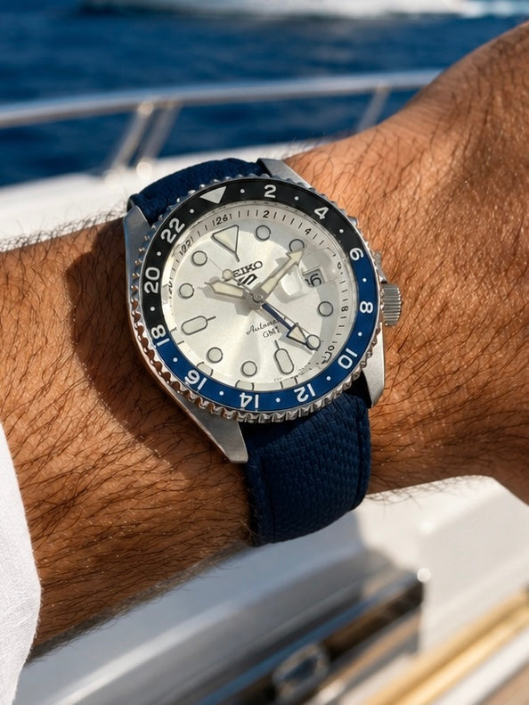 Bracelet de montre FKM bleu texture Sailcloth monté sur une Seiko SSK033K1, photographié au poignet sur le pont d’un yacht.