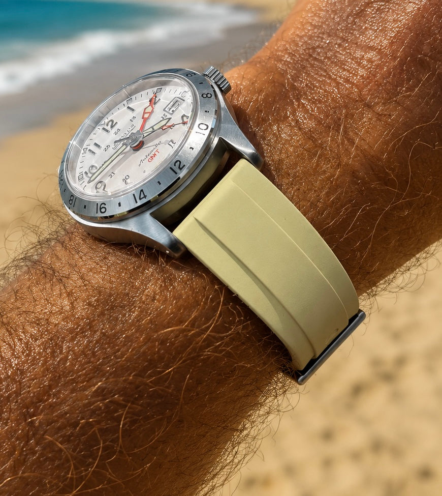 Bracelet de montre FKM kaki compatible Submariner Oyster, monté sur une montre à cadran blanc et porté au poignet sur une plage.